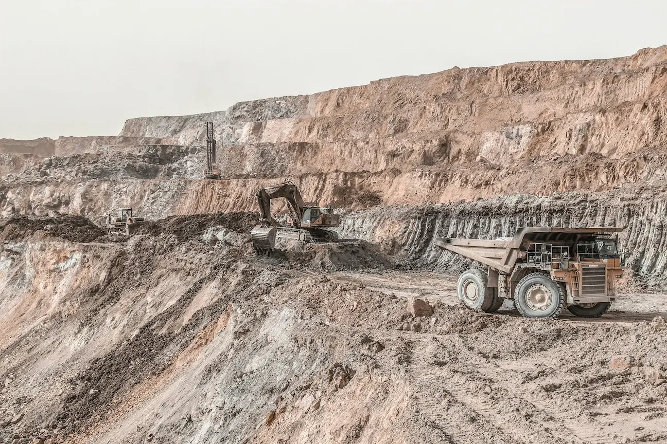 Large open pit mine with haul truck showing stages of mineral exploration